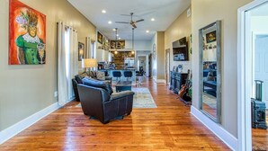 A spacious living area with hardwood flooring, a dark leather sofa, and a kitchen in the background.