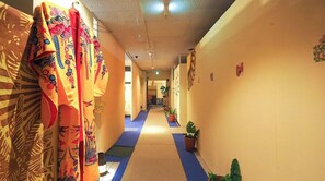 A hallway with patterned curtains, potted plants, and a blue carpet.