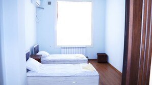 A room with two beds, a radiator, a window, and a door. - Ozbek Hotel (Andijan)