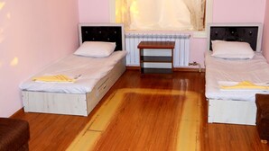 A room with two single beds, a wooden floor, a radiator, and a window with sheer curtains. - Ozbek Hotel (Andijan)