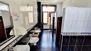 A bathroom with white and black tiles, two sinks, a toilet, and a mirror. - Ozbek Hotel (Andijan)