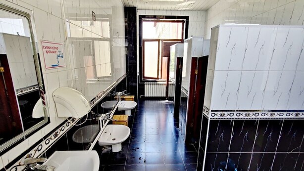 A bathroom with white and black tiles, two sinks, a toilet, and a mirror. - Ozbek Hotel (Andijan)