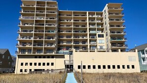 Un edificio residencial de varios pisos con balcones, un corredor cubierto y cielo despejado.