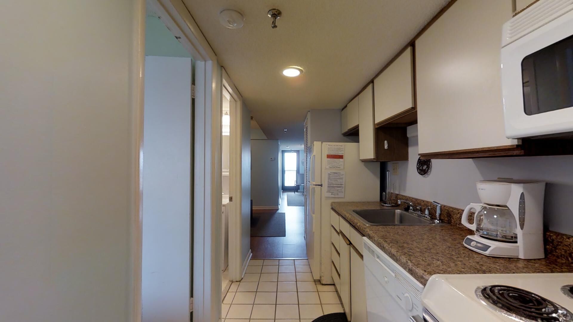 A narrow kitchen with a microwave, coffee maker, and a dishwasher.