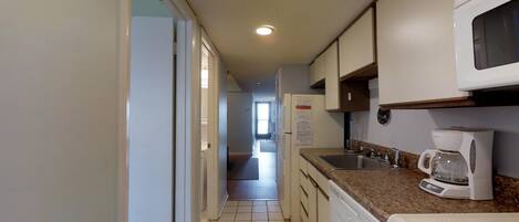A narrow kitchen with a microwave, coffee maker, and a dishwasher.