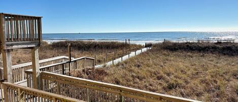 A wooden boardwalk leading to a beach with a clear view of the ocean.
