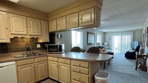 A spacious kitchen with wooden cabinets, a microwave, and a dishwasher. - Corner Oceanfront 2BR – Elevated Balcony Views - Cherry Grove - Beachmaster 107 (North Myrtle Beach)