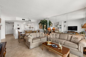 A spacious living room with a large sofa, a coffee table, and a dining area with chairs and a table.