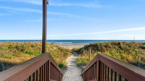 Un sentier en bois mène à une plage d’où l’on a une vue dégagée sur l’océan.