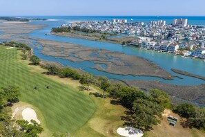 Un paysage urbain côtier comprenant un terrain de golf, des plans d’eau et des immeubles résidentiels.