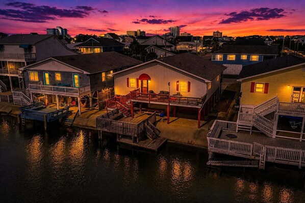 A waterfront property with docked boats, a covered deck, and a building with a red door.