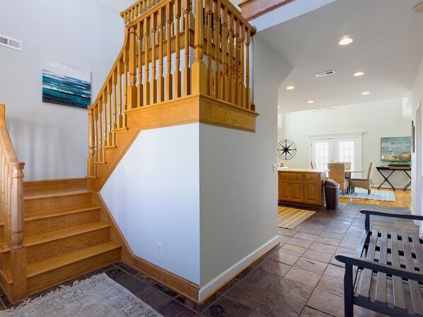 Un escalier en bois menant à un deuxième étage, une cuisine avec des meubles en bois et un coin repas avec un banc.