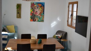 A dining area with a wooden table and black chairs, a woven hanging light fixture, and a colorful abstract painting on the wall. - Typical Andalusian house in the heart of the historic center (Almuñécar)
