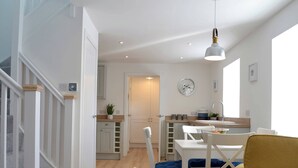 Una cocina moderna con armarios blancos, un reloj y un comedor con una mesa y sillas.