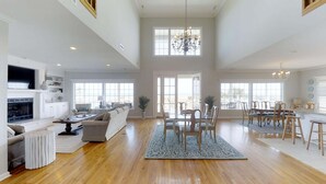 A spacious living area with a fireplace, seating, and a dining area with chairs and a table.