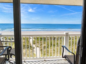 A balcony with a view of the beach and ocean.