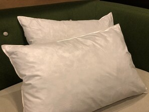 Un lit avec deux oreillers blancs et une tête de lit verte.