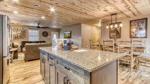 Une cuisine spacieuse dotée d’un plan de travail en granit, d’un plafond en bois et d’un coin repas avec des meubles en bois.