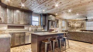 Une cuisine spacieuse avec un grand îlot central, des tabourets de bar et un plafond en bois.
