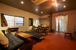 A room with a bed, a desk, a chair, a table, and a large window.
