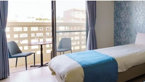 Relax in this inviting room with a large bed, a dining table, and a window offering a view of the surrounding cityscape.