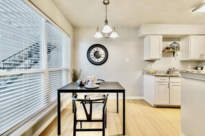 A modern kitchen with white cabinets, a black clock, and a dining area with a table and chairs.