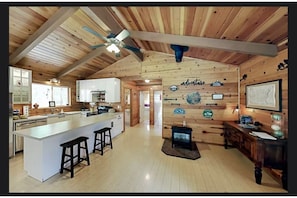 Une cuisine spacieuse avec un grand îlot central, des poutres apparentes en bois et une décoration rustique.
