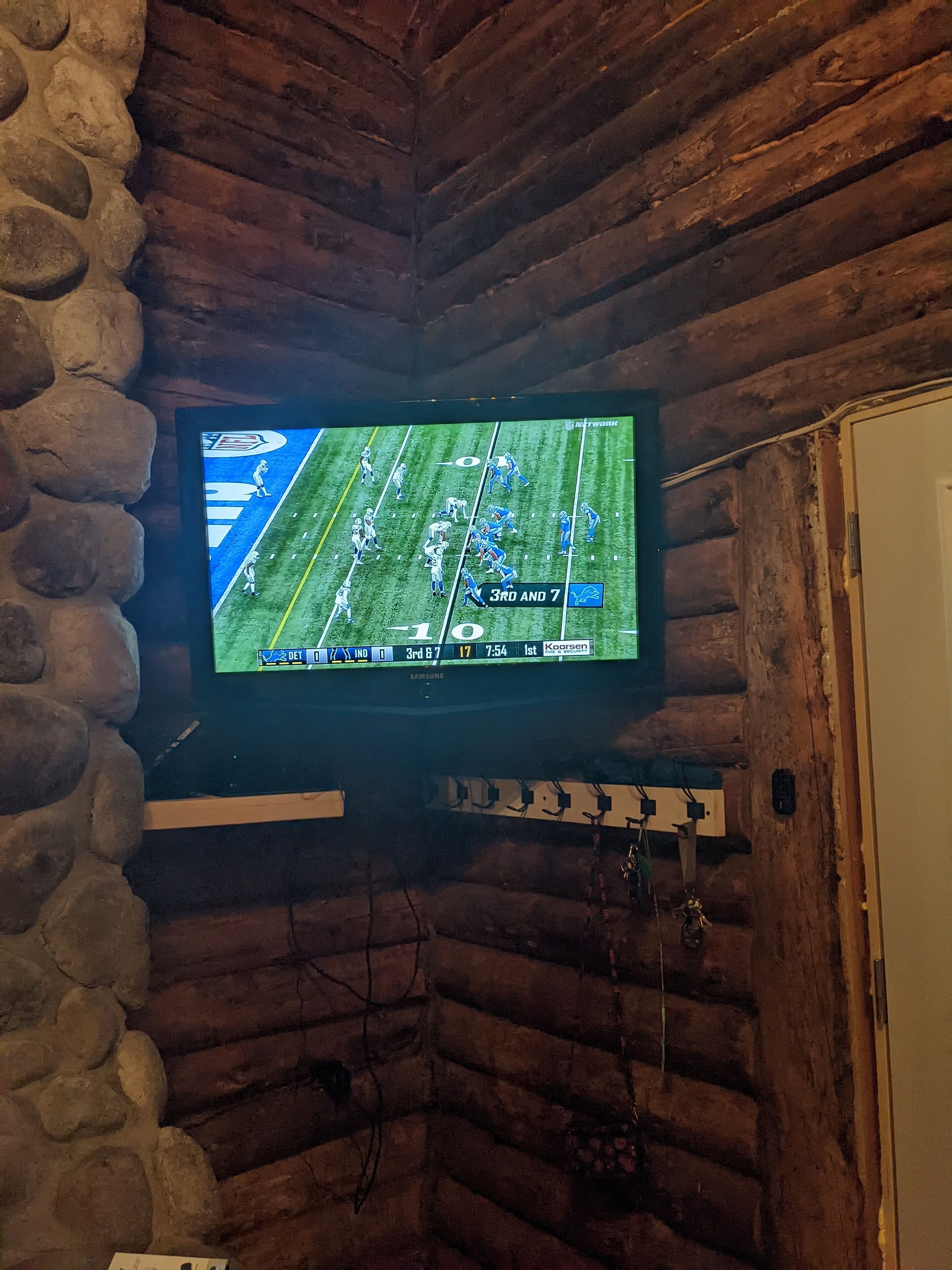 Un televisor montado en una pared de piedra en el interior de una cabaña de troncos.