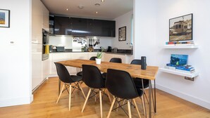 Eine moderne Küche mit dunklen Schränken, einem Holztisch mit schwarzen Stühlen und einem Blumentopf.