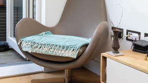 Ein modernes Zimmer mit einem braunen Ledersessel, einem kleinen Holztisch und einer weißen Wand.