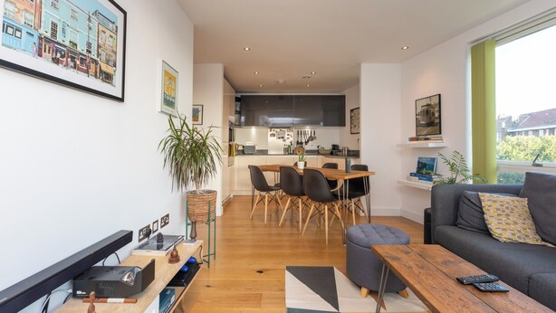 Ein modernes Wohnzimmer mit Sofa, Couchtisch und Essbereich mit Tisch und Stühlen.