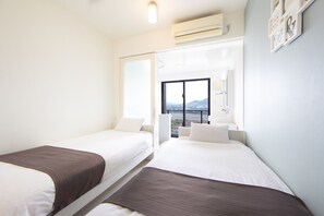 Una habitación de hotel con dos camas, un ventanal grande y un equipo de aire acondicionado.