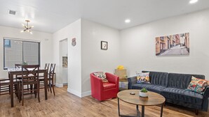 A living room with a dining area, a red armchair, a gray sofa, and a round coffee table.