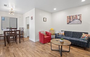 A living room with a dining area, a red armchair, a gray sofa, and a round coffee table.