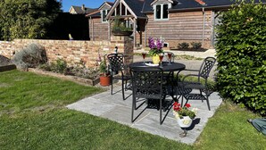 A patio with a table and chairs, a potted plant, and a brick wall.