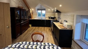 A kitchen with a wooden ceiling, a window, and a dining area with a patterned tablecloth.