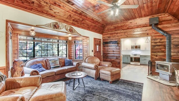 Interior d'una cabana de fusta amb saló, llar de foc i cuina.