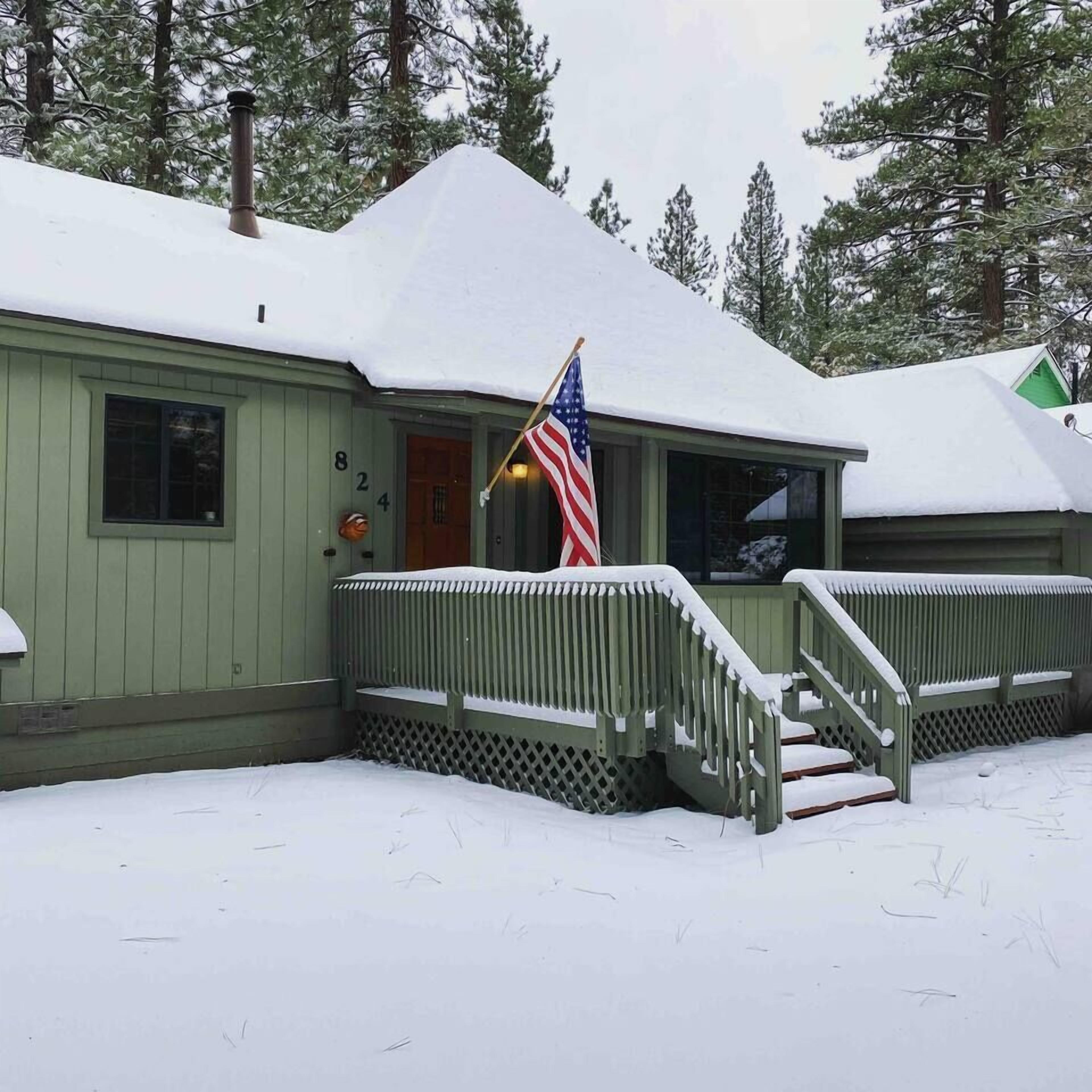 A green building with a snow-covered roof and a flag.