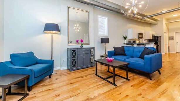 A spacious living room with a blue sofa, a coffee table, and a large mirror. - Medical District Gem i (Chicago)