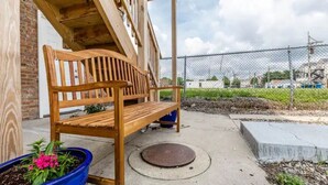 A wooden bench outside a building with a brick wall and a blue flower pot. - Medical District Gem i (Chicago)