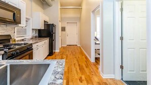 A modern kitchen with a central island, stainless steel appliances, and hardwood flooring. - Medical District Gem i (Chicago)
