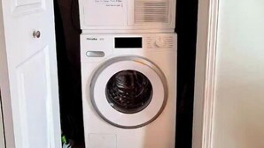A stacked washer and dryer unit in a narrow hallway. - Medical District Gem i (Chicago)