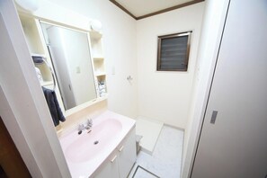 Ein Badezimmer mit weißem Waschbecken, Spiegel, Fenster und Dusche.