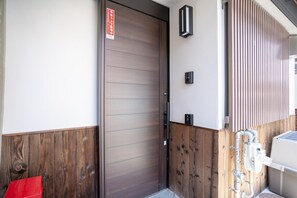 A closed sliding door with a sign, a wall-mounted light fixture, and a wooden panel with a white pipe.