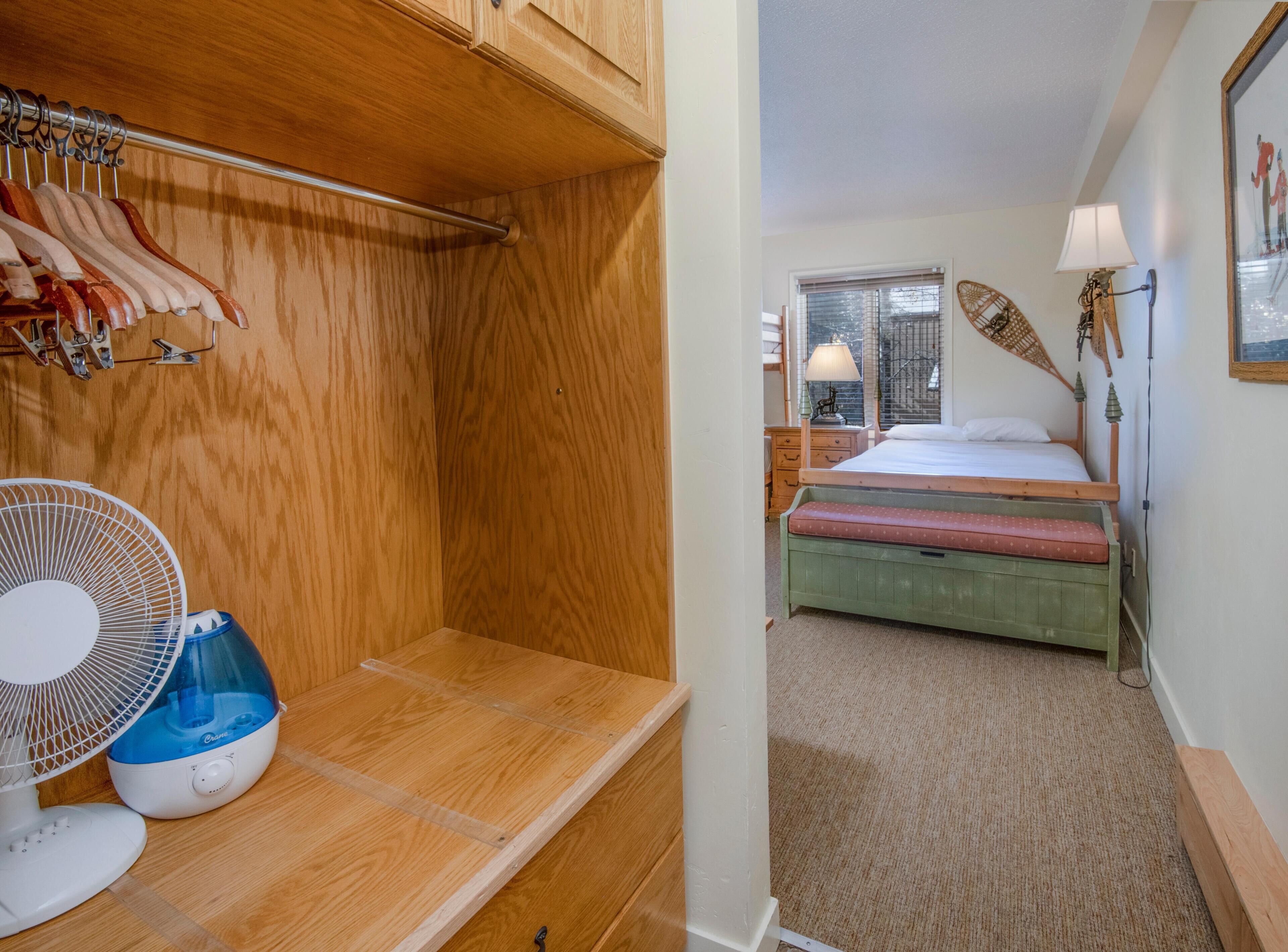 A compact room with a bed, bedside lamp, and a fan.