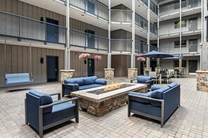 A multi-level outdoor patio with stone flooring, blue seating, a fire pit, and a dining area with umbrellas. - Westwind 306 2BD 2BA Gold Condo in Lionshead Village (Vail)