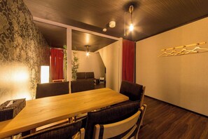 A modern dining area with a wooden table, dark upholstered chairs, and a hanging light fixture.