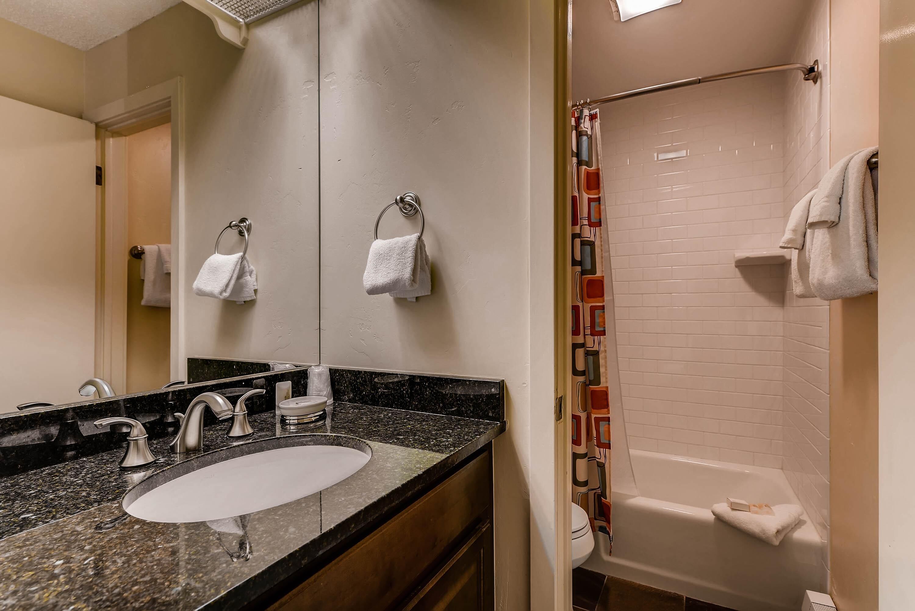 Un baño con lavamanos, espejo y ducha.