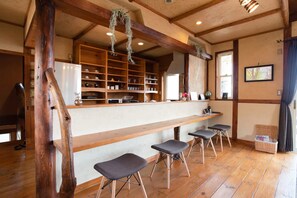 A rustic interior with a wooden bar, shelves with glassware, and a seating area with stools. - 5LDK with natural hot spring and the ocean view - Gift Villa / Beppu Ōita (Beppu)