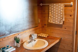 A wooden cabin bathroom with a sink, a towel rack with a polka dot towel, a small plant, and a cup. - 5LDK with natural hot spring and the ocean view - Gift Villa / Beppu Ōita (Beppu)